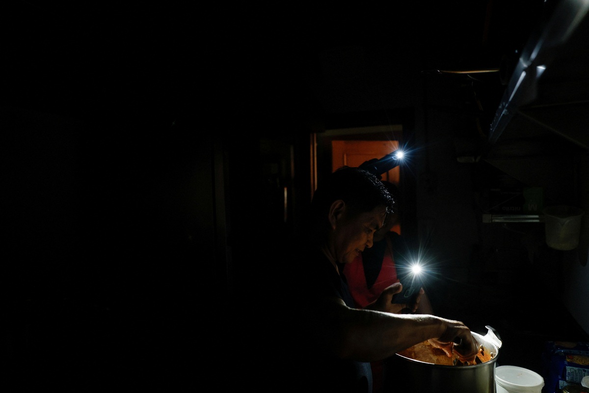 Un bucătar de la restaurantul „La Cocinona” lucrează într-o bucătărie întunecată cu ajutorul lanternelor telefoanelor, în timpul penei de curent în Madrid, Spania.